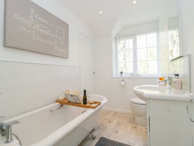 A bathroom with a bathtub a sink a toilet and a window at Duck Cottage in Sutton Poyntz