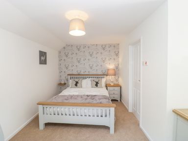 A bedroom with a double bed bedside tables a lamp and decorative pillows at Duck Cottage in Sutton Poyntz