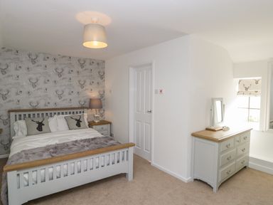 A bedroom with a bed a dresser a bedside table and a lamp at Duck Cottage in Sutton Poyntz