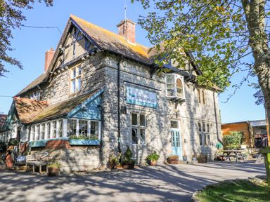 Stone building with a blue door and windows with flower pots outside and a sign saying The Springhead pub and restaurant