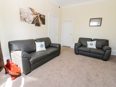 A living room with two dark sofas and nautical themed cushions at Sailors Lodge in Filey