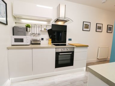 A kitchen with a microwave toaster and oven with framed pictures on the wall at Sailors Lodge in Filey