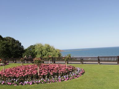 A garden with flower beds and benches overlooking the sea at Sailors Lodge in Filey