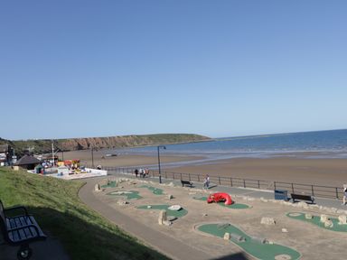 A mini golf course near a beach with people walking along a promenade at Sailors Lodge in Filey
