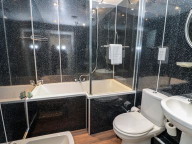 A bathroom with a bathtub shower combination a toilet and a sink at Coquet View Apartment in Warkworth