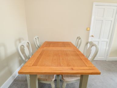 A dining room with a wooden table and four chairs next to a white door at Coquet View Apartment in Warkworth