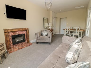 A living room with a sofa armchair and dining table with chairs at Coquet View Apartment in Warkworth
