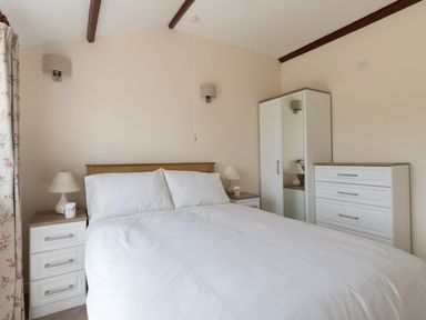 A bedroom with a bed bedside tables lamps a wardrobe and a chest of drawers at Village View in Burton Bradstock