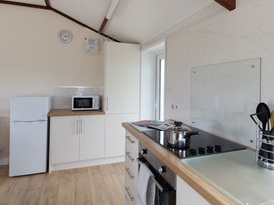 A kitchen with a refrigerator microwave oven stove and cooking utensils at Village View in Burton Bradstock