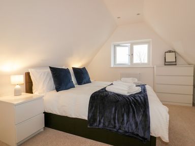 A bedroom with a double bed bedside table lamp and chest of drawers at Lily Cottage in Camelford
