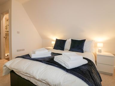 A bedroom with a double bed black pillows bedside tables and lamps at Lily Cottage in Camelford