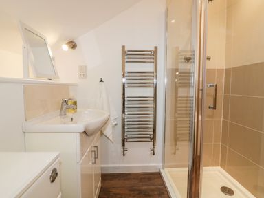 A bathroom with a sink cabinet towel rail and enclosed shower at Lily Cottage in Camelford