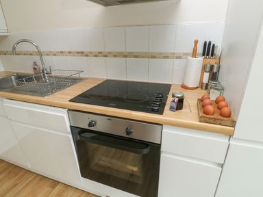 A kitchen countertop with a sink a stovetop an oven and eggs on a tray at Bantam Cottage in Little Woodford near Ottery St Mary