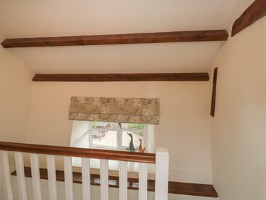 A staircase landing with a window and wooden beams at Bantam Cottage Little Woodford near Ottery St Mary