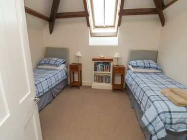 A bedroom with two single beds wooden nightstands and a skylight at Bantam Cottage Little Woodford near Ottery St Mary
