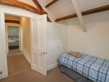 A small bedroom with a single bed and built in wardrobe at Bantam Cottage in Little Woodford near Ottery St Mary