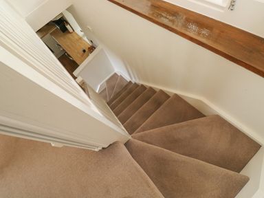 A carpeted staircase leading down to a kitchen area at Bantam Cottage in Little Woodford near Ottery St Mary