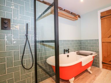 A bathroom with a red clawfoot bathtub and a glass shower partition at Tickmorend Farm in Nailsworth