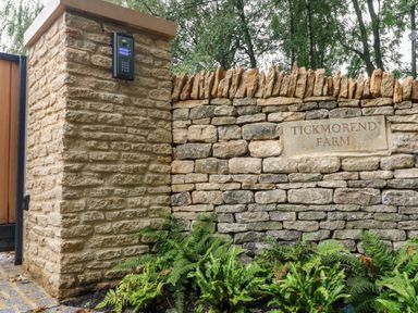 A stone entrance wall with a keypad and a sign reading Tickmorend Farm at Tickmorend Farm in Nailsworth