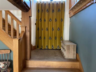 A staircase area with wooden stairs a wooden bench and yellow curtains with bee patterns at Tickmorend Farm in Nailsworth