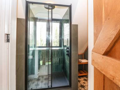 A tiled walk-in shower with glass doors in a bathroom at Tickmorend Farm in Nailsworth