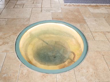 A round glass floor panel revealing a stone well below on a tiled floor at Tickmorend Farm in Nailsworth