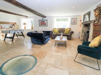 A living room with sofas foosball table and a fireplace at Tickmorend Farm in Nailsworth