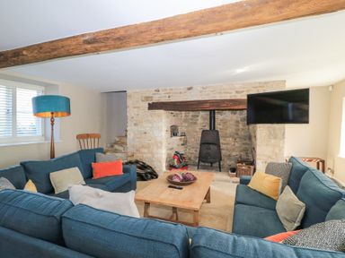 A sitting room with blue sofas a wooden coffee table and a wood burning stove at Tickmorend Farm in Nailsworth