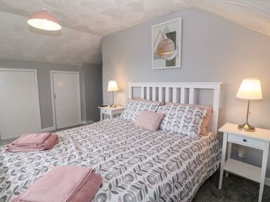 A bedroom with a double bed and two bedside tables with lamps at Buarthau Cottage in Llanrug