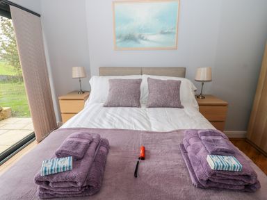 A bedroom with a bed two bedside tables with lamps folded towels on bed at Coal Drops in Alnwick