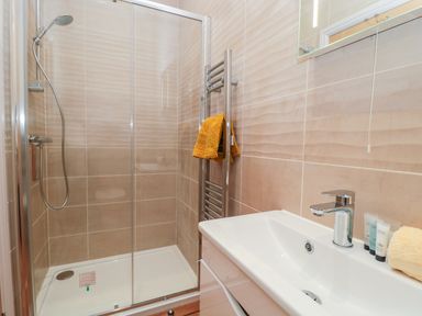 A bathroom with a glass-enclosed shower and a white sink with toiletries at Coal Drops in Alnwick