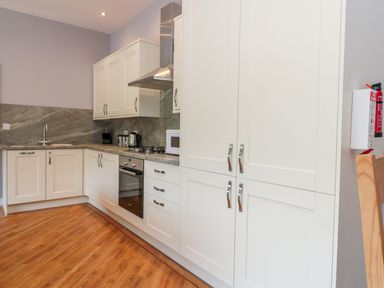 A kitchen with white cabinets countertop with kettle microwave and stove at Coal Drops in Alnwick