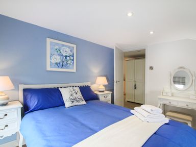 A bedroom with a bed with blue bedding and white furniture at Amolca in Llaneilian