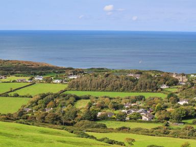 A coastal village with houses fields and trees overlooking the sea at Amolca in Llaneilian
