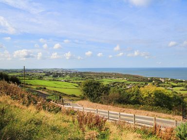 A coastal landscape with green fields trees and a road at Amolca in Llaneilian