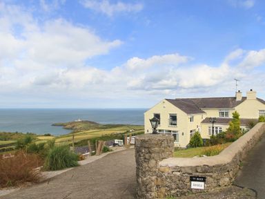 A house with a stone wall and lamp post overlooking the sea at Amolca in Llaneilian