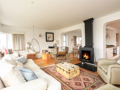 A living room with a sofa armchairs a hanging bubble chair a fireplace and a patterned rug at Angorfa - Trearddur Bay
