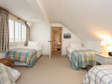A bedroom with two single beds with plaid blankets and a nightstand with a lamp at Angorfa - Trearddur Bay in Trearddur Bay
