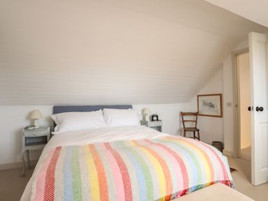 A bedroom with a bed and colorful striped blanket at Angorfa - Trearddur Bay