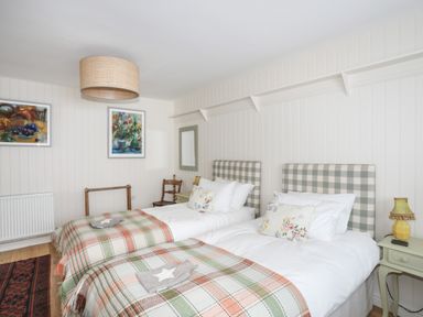 A bedroom with two single beds with plaid headboards and checkered blankets at Angorfa - Trearddur Bay