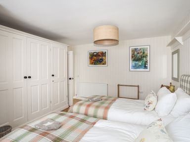 A bedroom with two single beds blankets on beds wardrobes and framed pictures on wall at Angorfa - Trearddur Bay