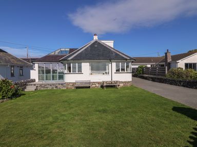 A house with a large front lawn a wooden bench and picnic table at Angorfa  Trearddur Bay