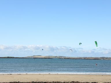 A beach with people kite surfing in the water at Arkoo in Rhosneigr