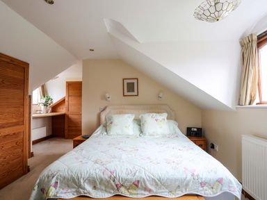 A bedroom with a double bed and butterfly patterned bedding at Barras Cottage in Brynsiencyn