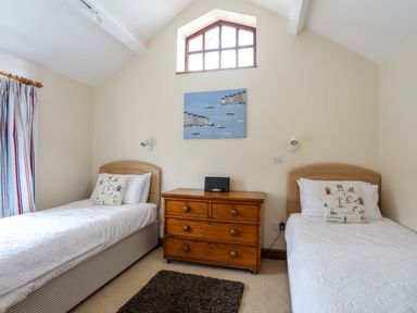 A bedroom with two single beds and a wooden chest of drawers at Barras Cottage in Brynsiencyn