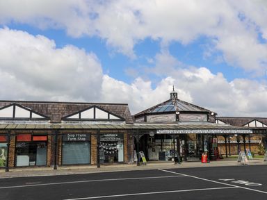 An exterior view of a building with a farm shop and a sign with a long name above the entrance at Barras Cottage in Brynsiencyn