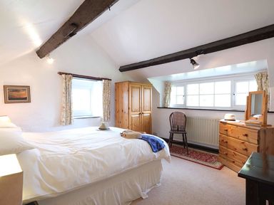 A bedroom with a bed wardrobe chair and chest of drawers at Foel Stable Cottage in Brynsiencyn