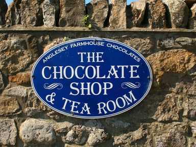 A blue oval sign with white text on a stone wall at Foel Stable Cottage in Brynsiencyn
