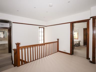 A landing area with wooden railing and doorways leading to a bathroom and bedroom at Bryn Deryn in Criccieth