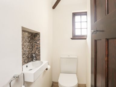 A small bathroom with a toilet sink and window at Bryn Deryn in Criccieth